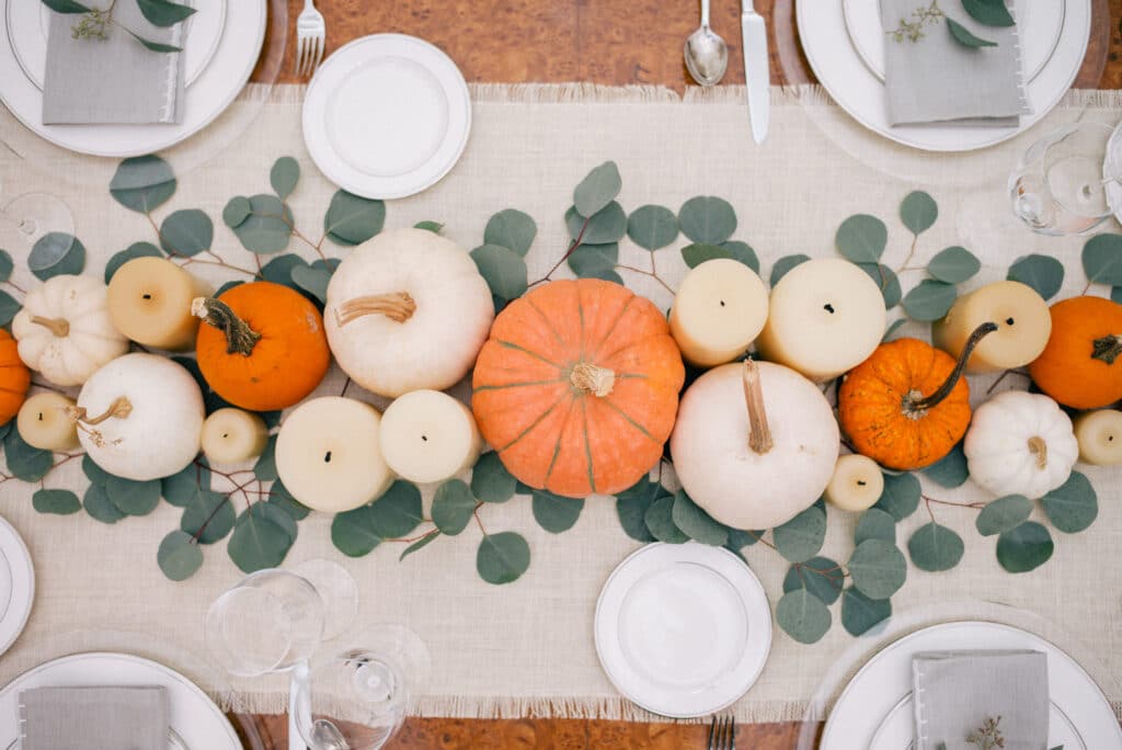 pumpkins, candles, and greenery on a Thanksgiving table